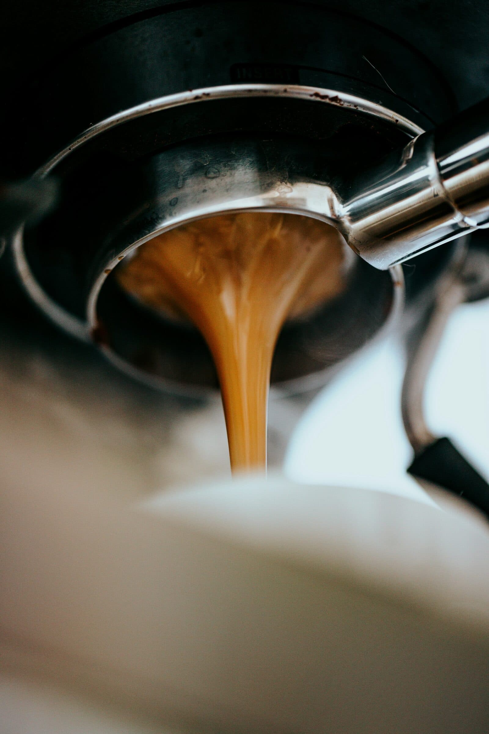 A thick stream of espresso pouring from a portafilter.