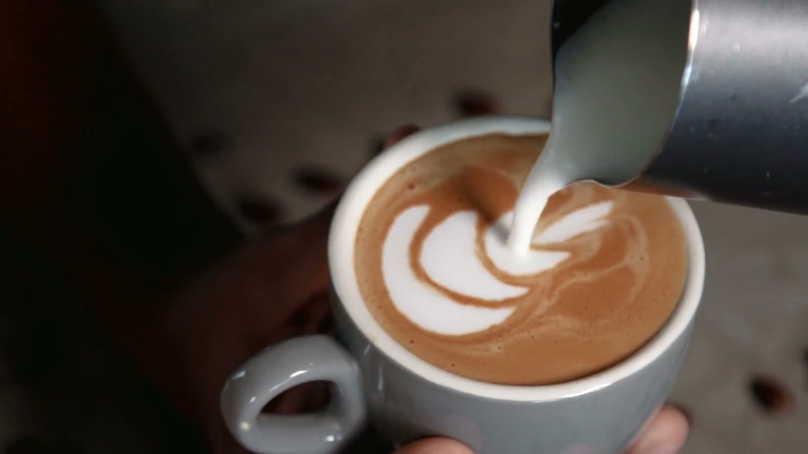 Milk poured into espresso, forming latte art in the cup.
