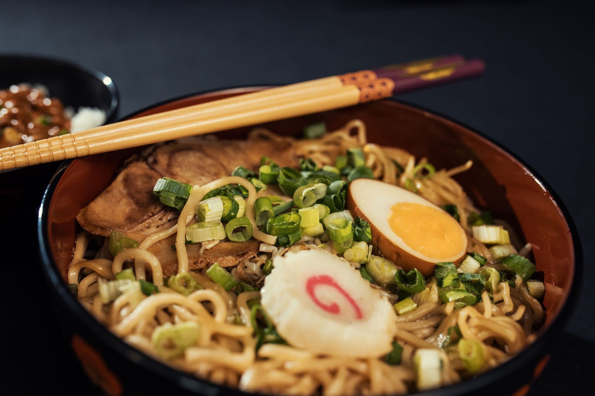Ramen topped with a soft egg, scallions and fish cake.