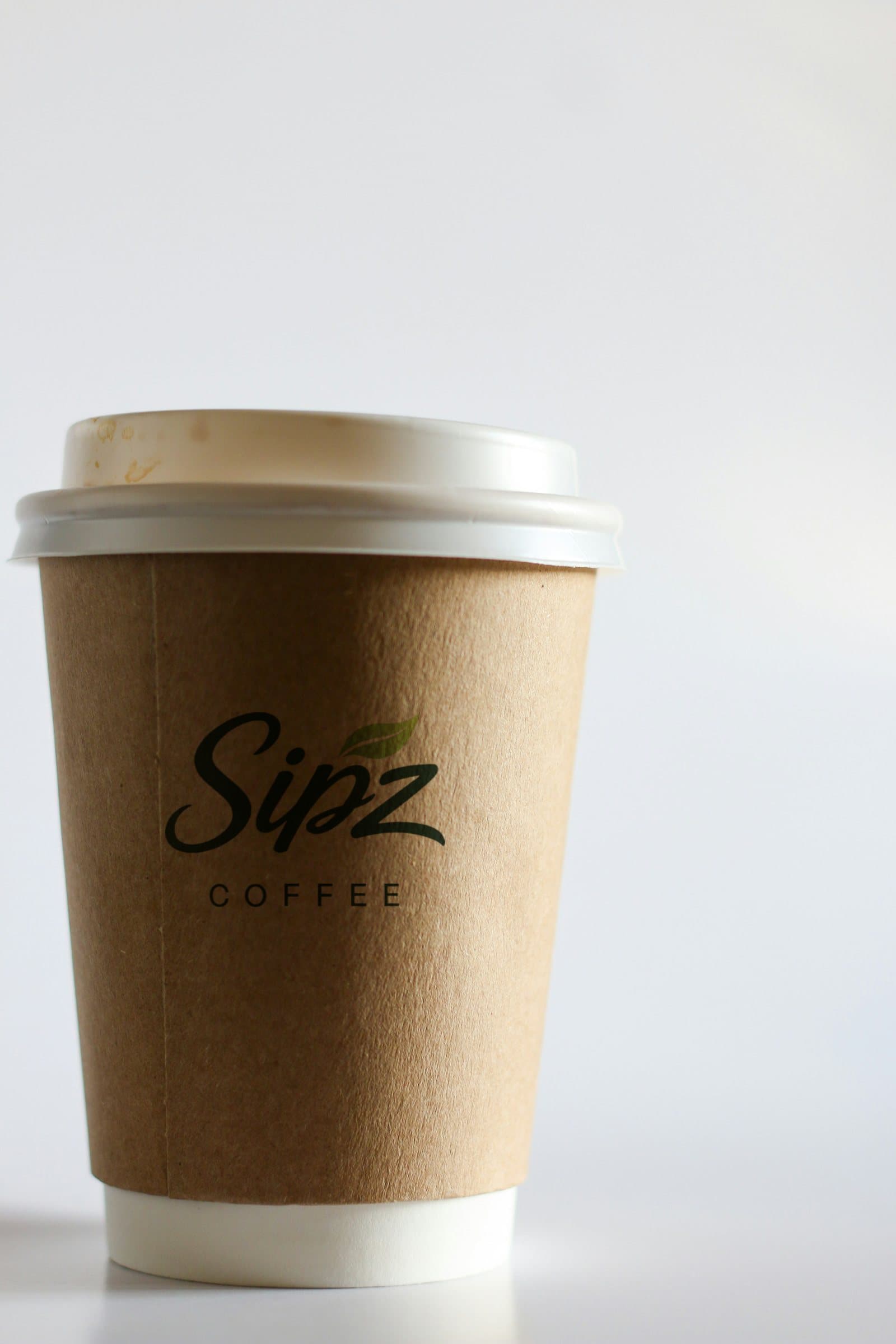 A kraft paper SIPZ coffee cup with a white lid.
