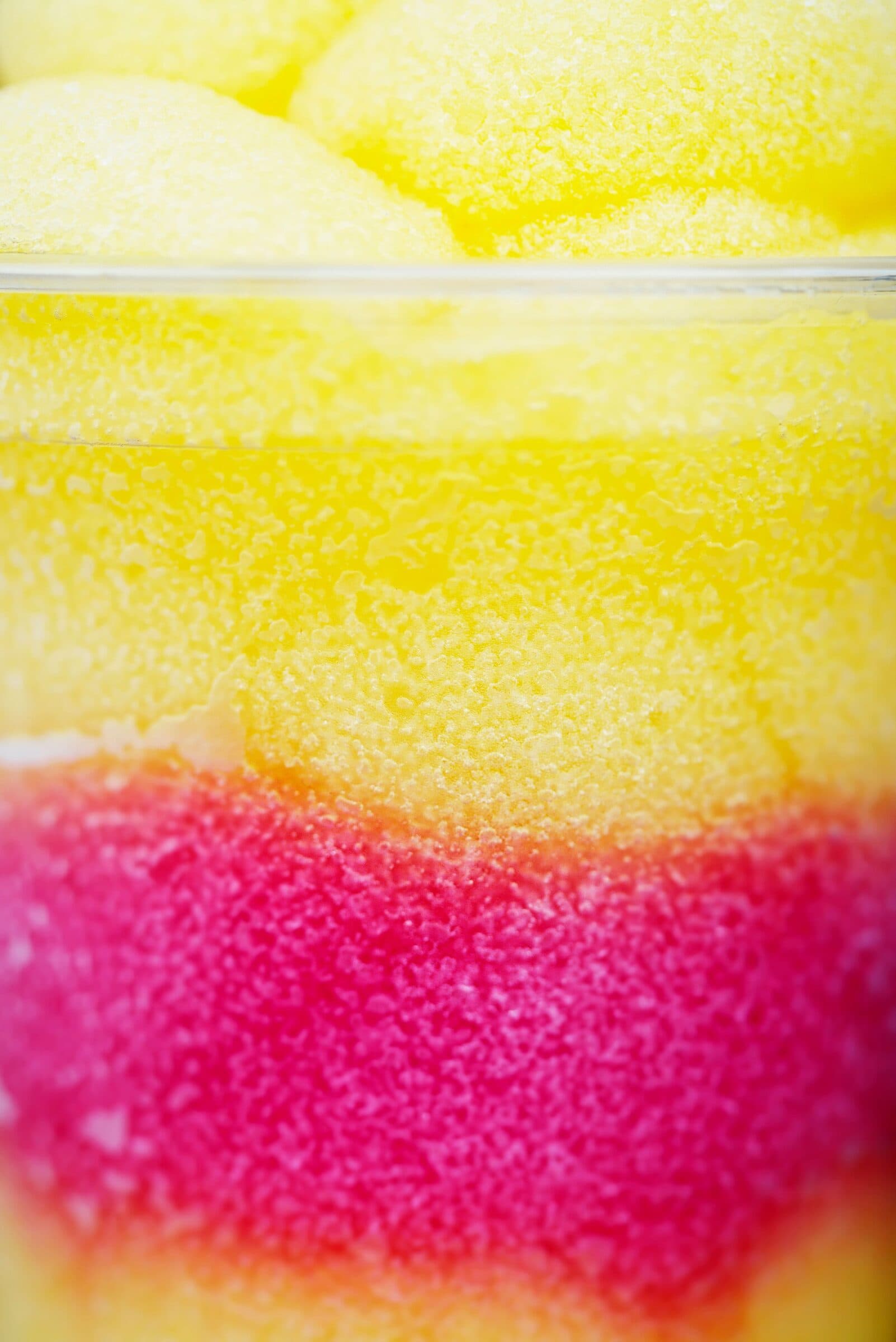 Close-up of yellow and red frozen slush layered in a cup.