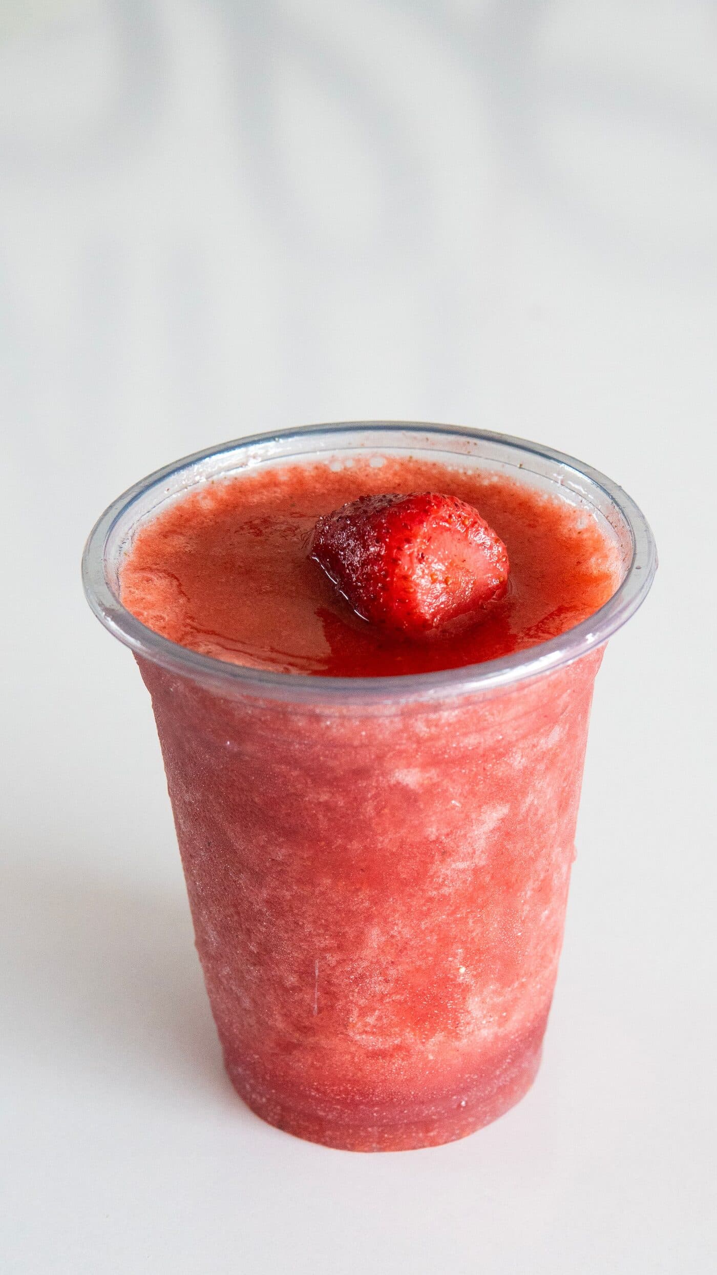 A strawberry slush in a clear plastic cup.
